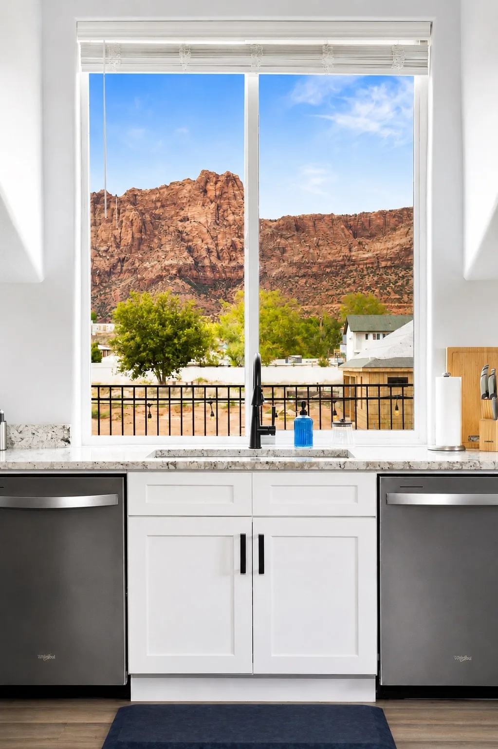 Sky Suite kitchen window over dual stainless dishwashers framing red-rock cliffs and the private upstairs balcony.